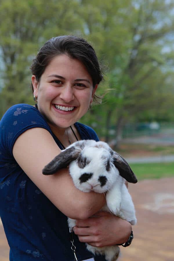 A young woman smiles and holds a large fluffy rabbit